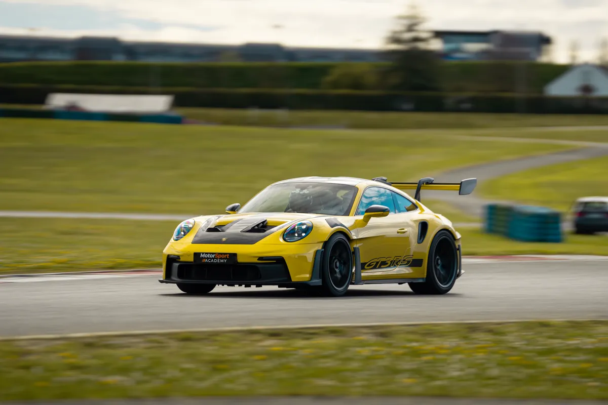 Porsche 911 GT3 RS jaune en courbe, décor filé par la vitesse